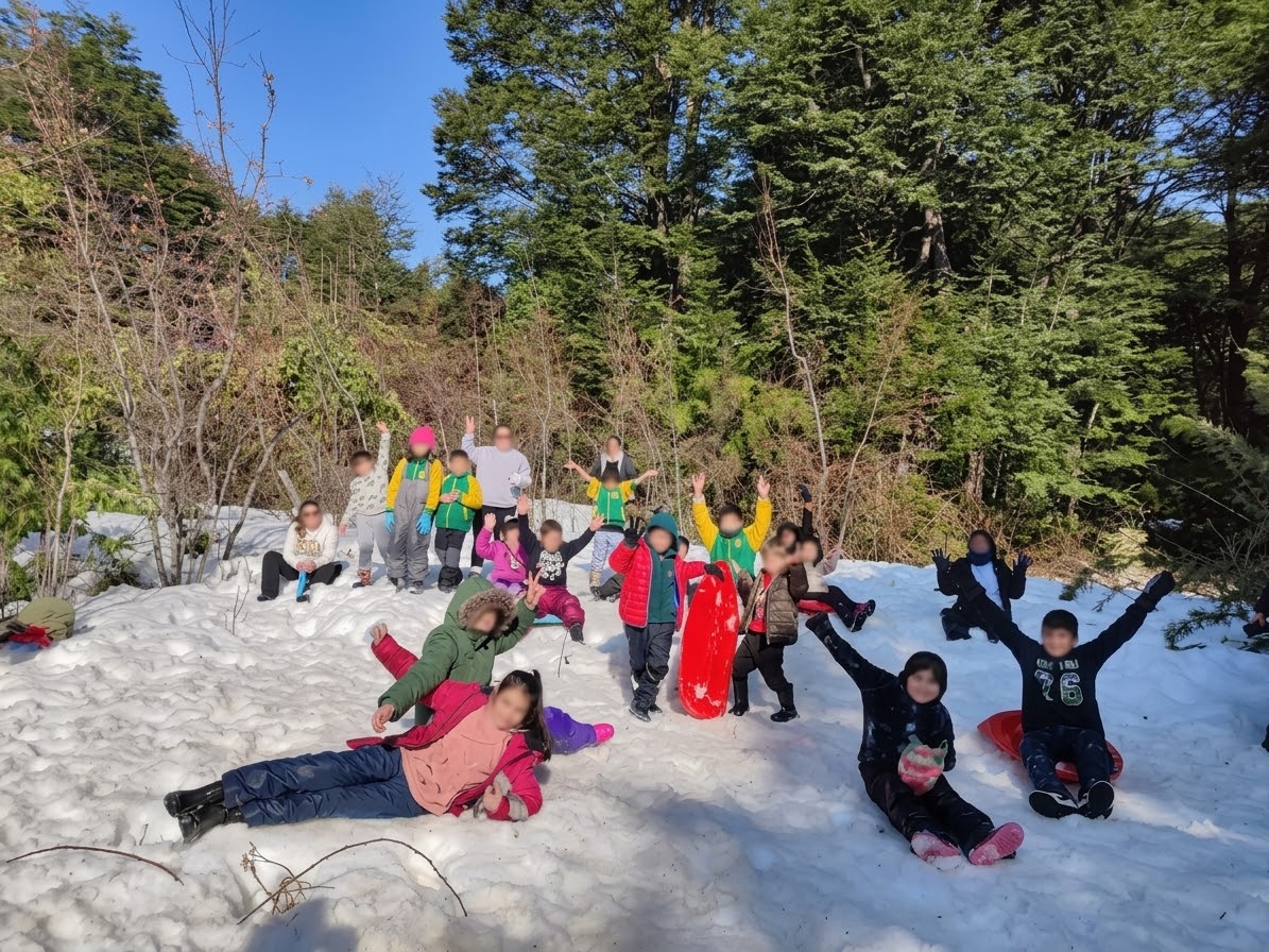 Estudiantes disfrutando de la nieve durante una actividad extracurricular en el bosque